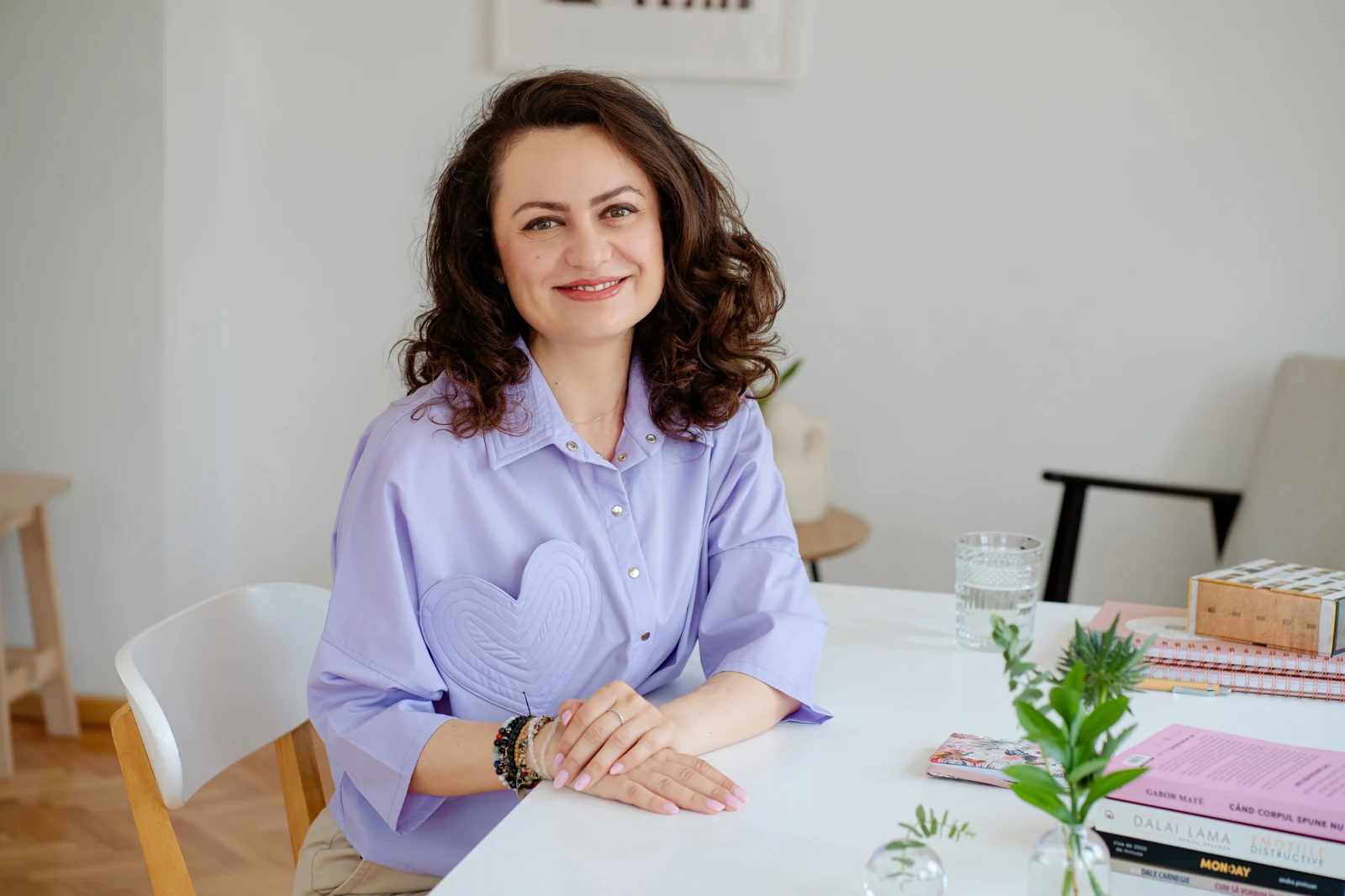 Alina Stan sitting at a desk in a lilac shirt